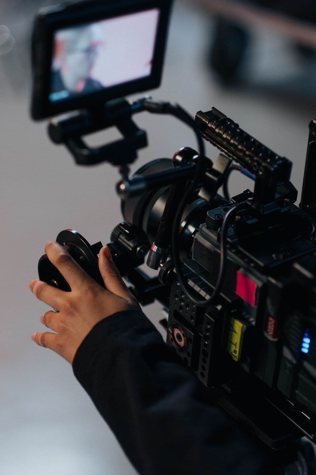 Hands adjusting a cinema camera on set.