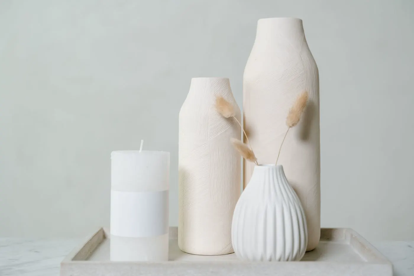 White ceramic vases and a pillar candle.